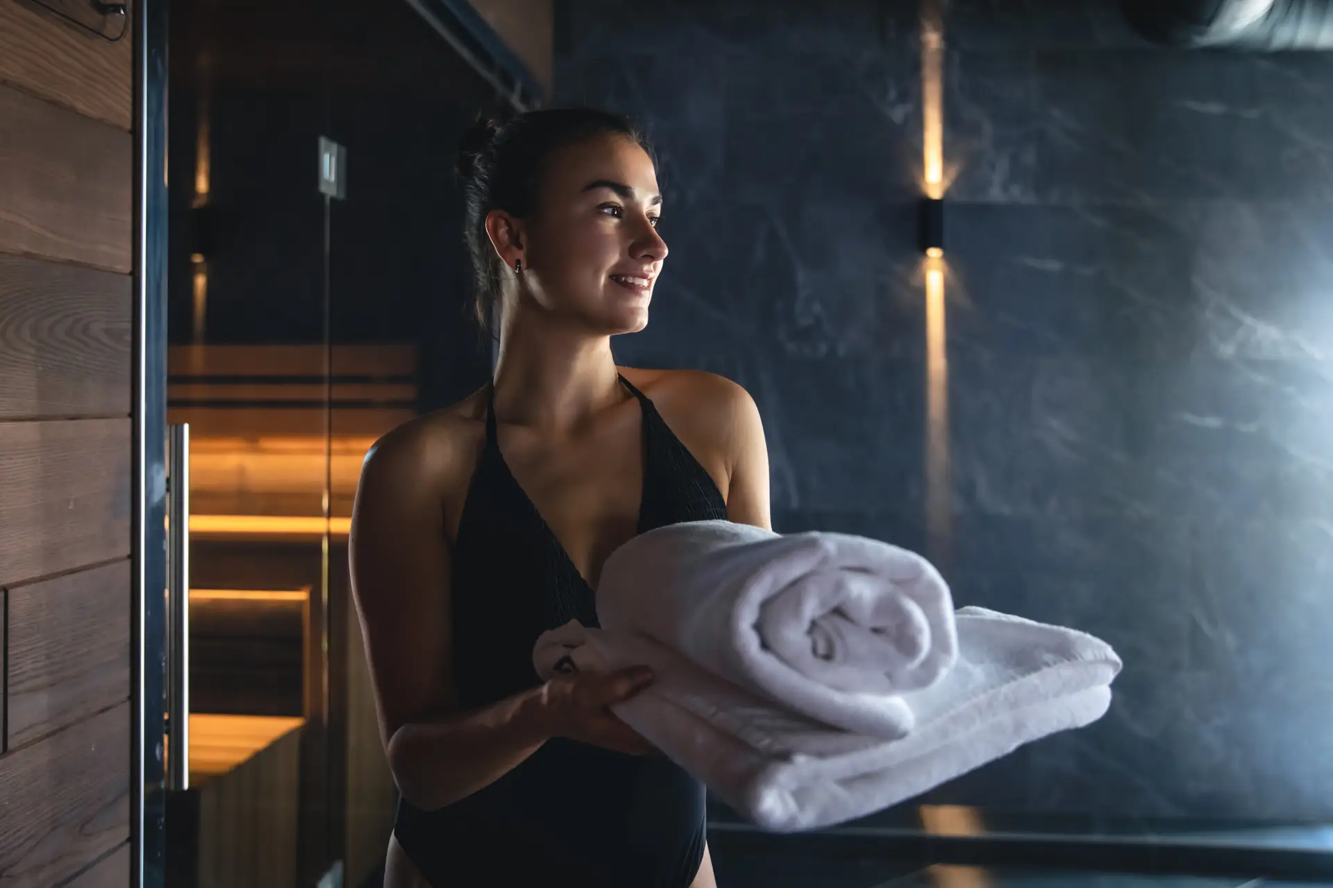Attractive young woman with towels is relaxing in the sauna.
